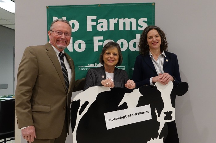State leaders pose with wooden cow and No Farms No Food banner at New York State Capitol. 