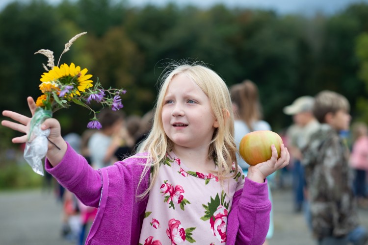 Young girl holds flower and apple